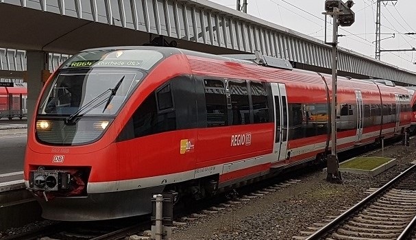 Ein roter Dieseltriebwagenzug vom Typ BR643 auf der Linie RB64 mit Ziel Enschede in den Niederlanden steht an einem Bahnsteig.