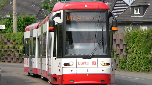 Ein weiß-roter Niederflurstraßenbahnwagen vom Typ NGT8 fährt über Straßenbahngleise.