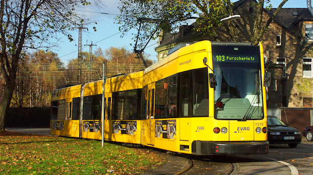 Ein gelber Niederflur-Stadtbahnwagen vom Typ M8D-NF biegt in herbstlicher Kulisse um eine Kurve.