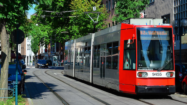 Ein rot-silberner Niederflur-Straßenbahnwagen vom Typ R1.1 fährt über Straßengleise. 