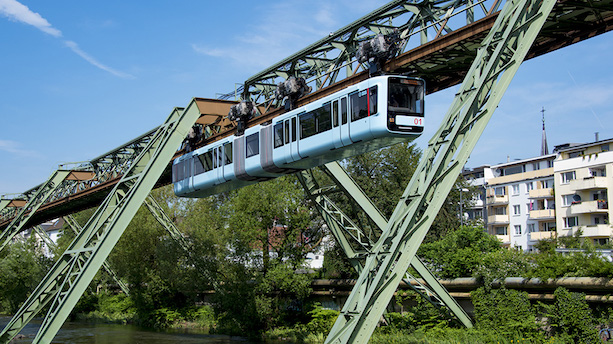Ein blauer Schwebebahnzug vom Typ GTW15 fährt entlang der Gleise in Wuppertal.