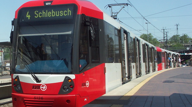 Ein rot-weißer Stadtbahnwagen vom Typ K5000 steht an einem Bahnsteig.