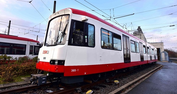 Foto eines rot-weißen Stadtbahnwagens vom Typ Vamos HF, der über Gleise fährt.