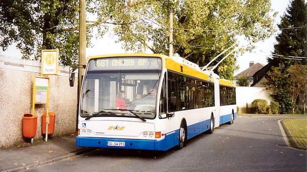 Ein weiß-blau-gelber Oberleitungsbus steht an einer Bushaltestelle.