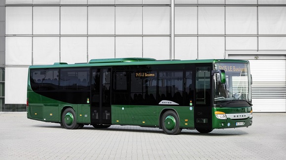 Ein grüner Überland-Standardbus von Setra steht vor einer Halle.