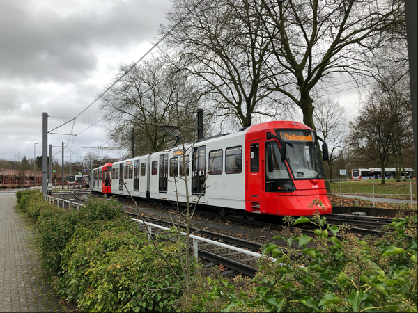 Ein rot-weißer Stadtbahnwagen vom Typ HF6 fährt Gleise entlang.