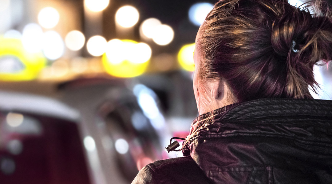 Blick über die Schulter eine Frau auf einen Taxistand bei Nacht.